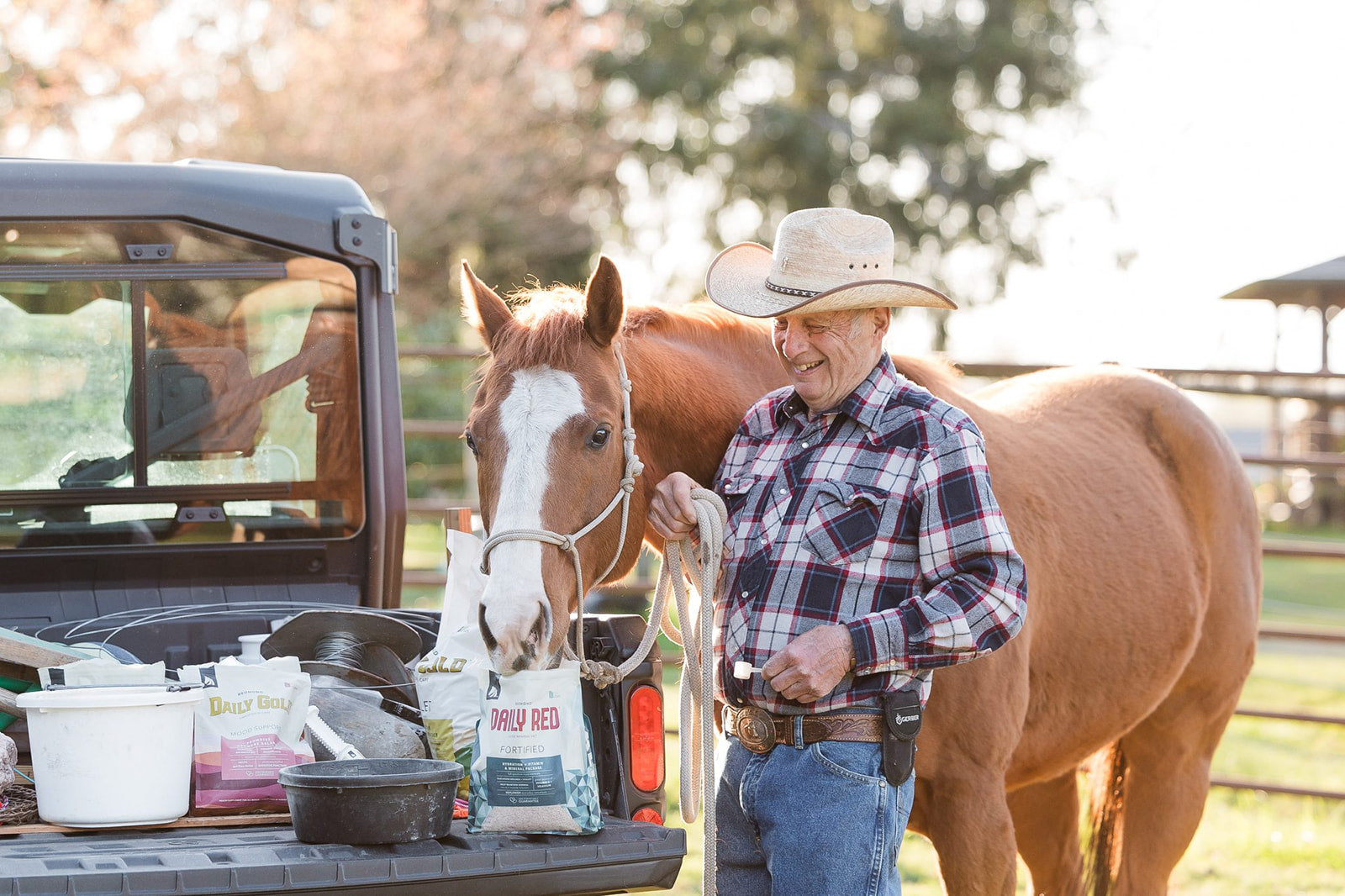 A smiling older man holds a lead rope on a horse smelling a bag of Daily Red Fortified—Redmond's vitamin and mineral supplement for horses.